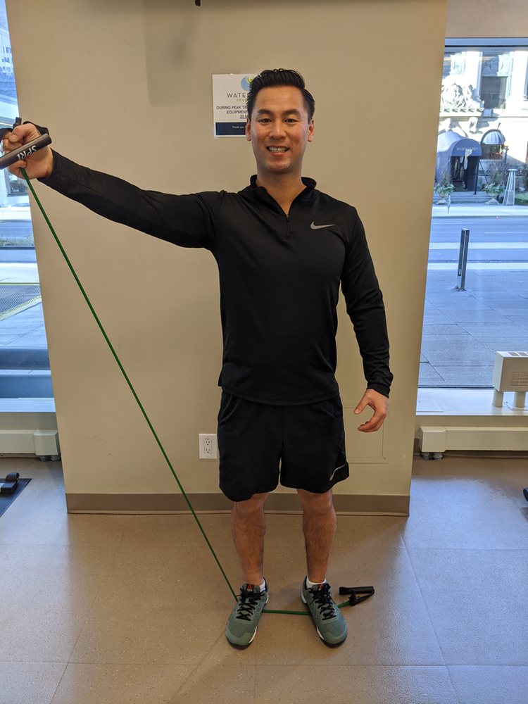 Physiotherapist Eric Lau demonstrating a banded shoulder abduction exercise.