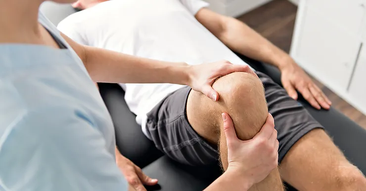 Physiotherapist stretching a patients knee after a total knee replacement.