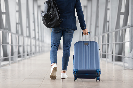 Unrecognizable Man With Bag And Suitcase Walking In Airport Terminal, Rear View Of Young Male On His Way To Flight Boarding Gate, Ready For Business Travel Or Vacation Journey