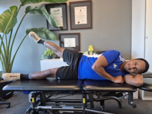 Physiotherapist Najih Ismail demonstrating a glut medius leg lift exercise.