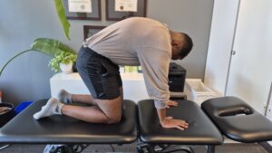 Physiotherapist Najih Ismail demonstrating the camel portion of a cat camel exercise