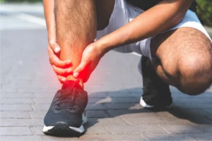 male runner crouching down and suffering from ankle impingement