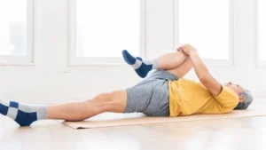 man stretching his lower back by bringing his knee up to his chest